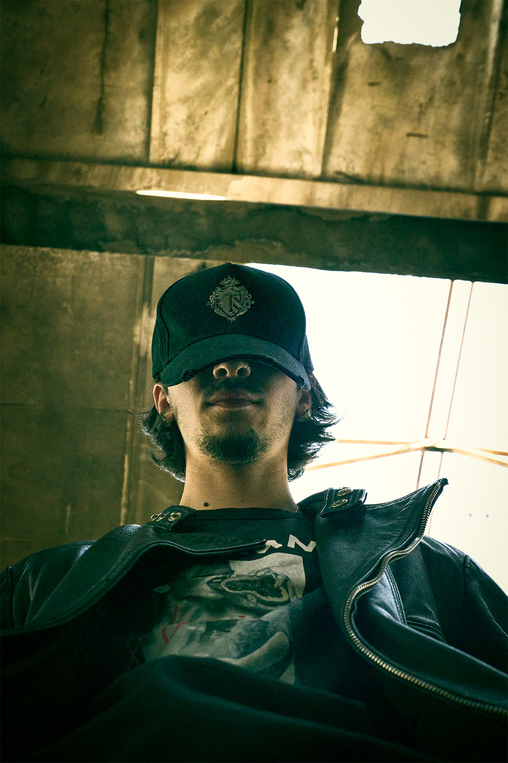 Low angle shot of a man wearing a black Trips signature cap and graphic t-shirt, representing Eastern European urban streetwear.